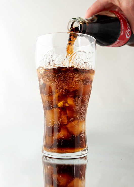 Pack shot of coca-cola being poured into a glass